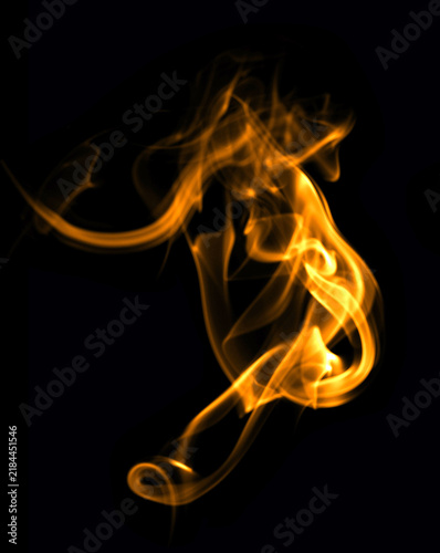 Quadro su tela Abstract orange smoke and glowing flame wisps swirling on a deep black background, creating a dramatic fiery texture for energy, motion, fantasy, technology, and creative design projects
