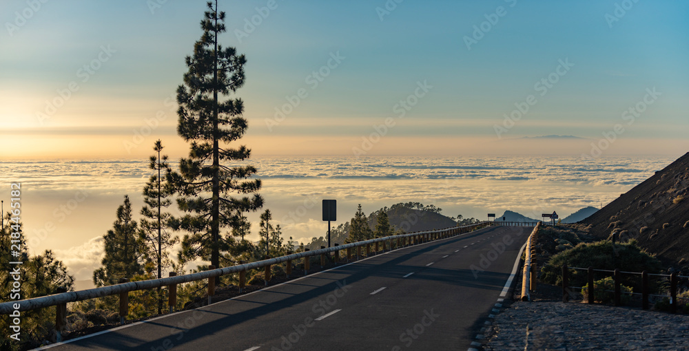 Naklejka premium Tenerife volcanic peak dominates landscape. Tenerife scenic road crosses lava field. Spectacular Tenerife mountain attracts tourism. Tenerife volcanic terrain inspires photographers.