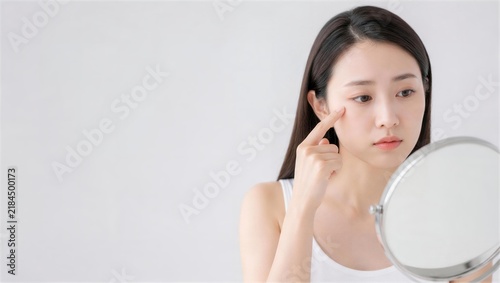 卓上鏡を見ながら目尻に指を添える女性