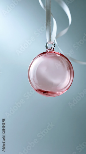 Pink glass ornament hanging from a ribbon indoors