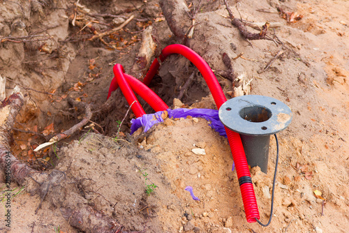 Obraz na plátně Vibrant red corrugated plastic conduit pipes installed underground in a dirt tre