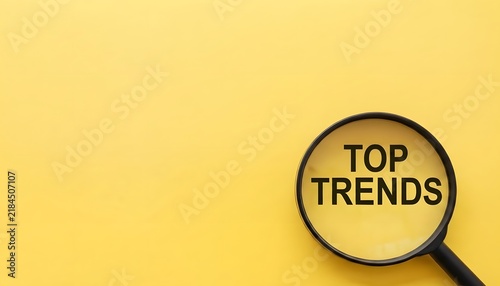 TOP TRENDS text written on magnifier glasses, on yellow background.