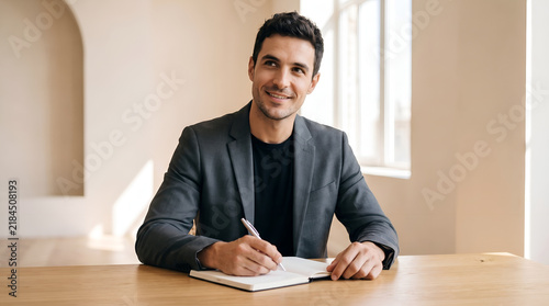 Professional Man Writing in notebook at wooden desk in modern office, businessman, business, planner, career, productivity