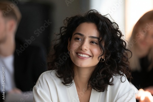 Young woman with curly hair smiling during a meeting in a bright corporate office setting