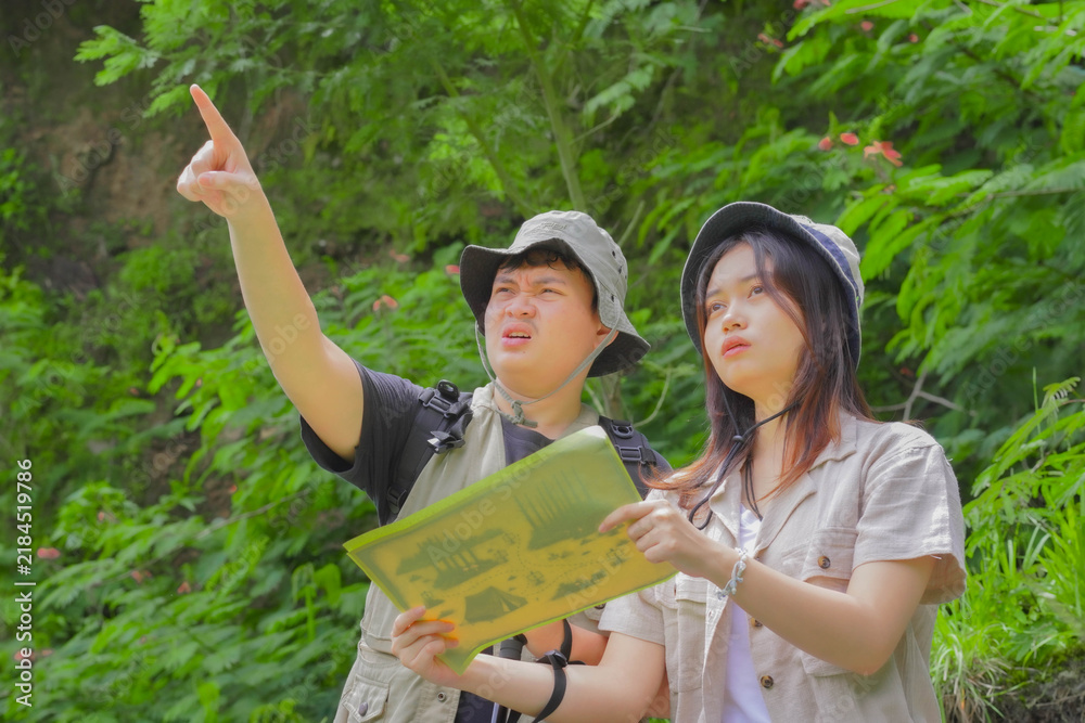 Fototapeta premium Young Asian couple is examining a hiking trail map they brought with them.