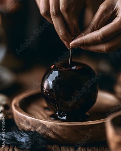 POV Hands Placing Dark Glossy Poison Apple for Halloween.