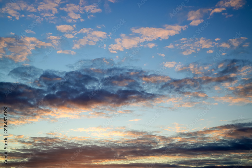 Fototapeta premium dramatic sunset with dense dark cloud formations illuminated by soft orange peach glow