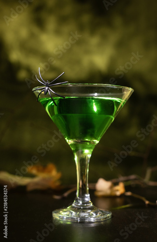Sticker Green cocktail in a martini glass on a dark background, Halloween-themed drink shot for party visuals and backgrounds