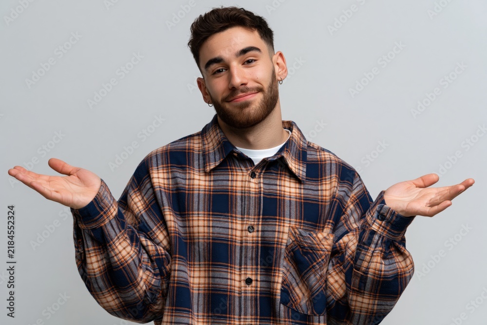Naklejka premium Smiling young man shrugging with palms up in a plaid shirt for social content and relaxed lifestyle banner imagery