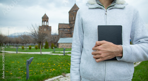 Bild auf Leinwand Caucasian man holding a book over church background. Religion