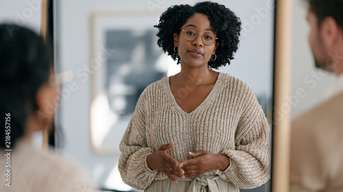Executive presence coach guiding a South African businesswoman through a posture and voice projection exercise in a corporate training room, standing tall before a full length