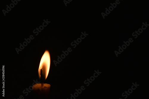 Bild auf Leinwand A solitary candle flame blowing gently in the wind against a pitch-black backgro