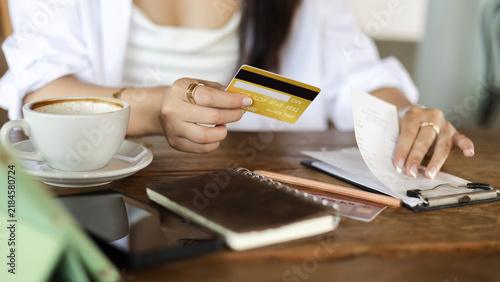 close-up shot, hand of young female holding credit card and checking financial bills, receipt before paying credit card debt