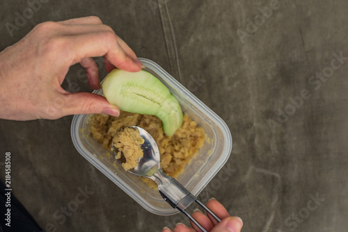 Принти на полотні Close view of young woman holding cucumber slice beside spoon and food container