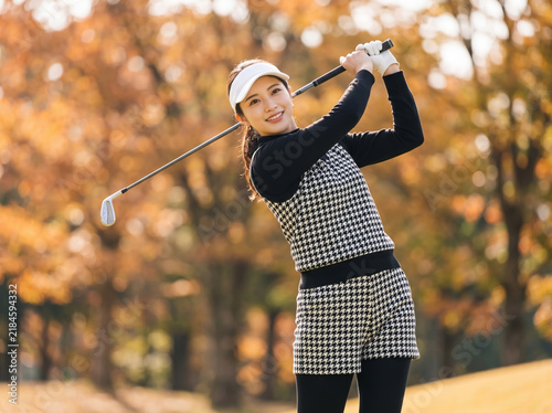 Naklejka 紅葉したゴルフ場でスイングを終え笑顔を見せる女性