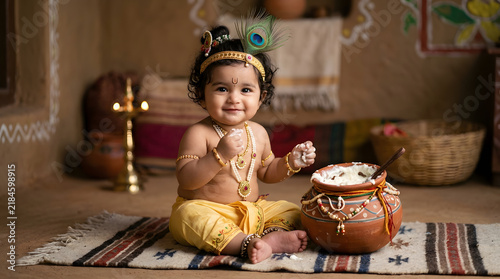 Cute baby boy dressed as lord krishna with a pot of butter