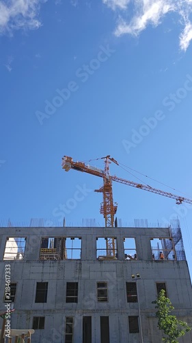 Time lapse of modern building construction showing a tower crane, concrete structure and progress of urban development under a blue sky, representing architecture, engineering and city growth