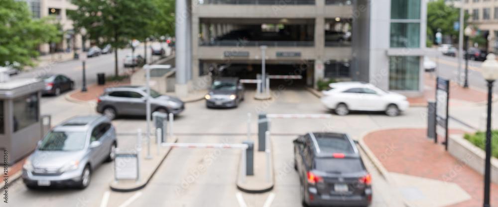 Fototapeta premium Fully blurred vehicles moving through the entrance and exit of a modern parking facility. Suitable for urban mobility, transportation, parking, traffic, infrastructure, and commercial background 