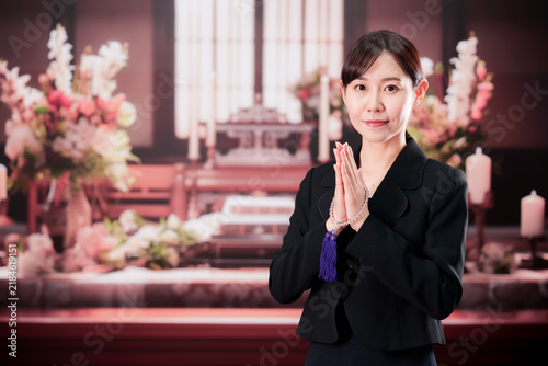 Fotografie お葬式で数珠をして手を合わせる女性
