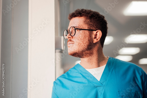 Nurse in blue scrubs looking away in a hospital corridor