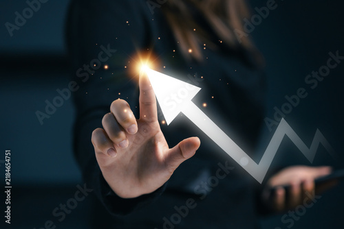 Business growth concept with person touching a glowing upward arrow on a digital interface, symbolizing progress, financial performance, strategy, opportunity, and positive results.