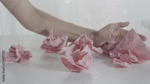 Hand remove pink crumpled paper from the table