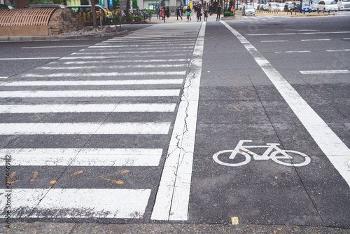Zebra crossing and bicycle lane symbol painted on an asphalt road at an intersection in Osaka, Japan.