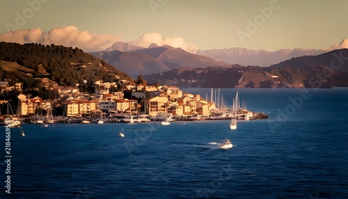 Scenic Coastal Village with Sailboats at Sunset.