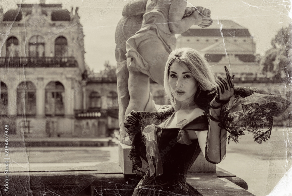 Obraz premium Beautiful blonde woman in gothic dress posing in vintage sepia photo style with scratched texture near classic baroque architecture 