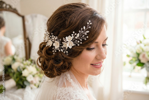 Young bride with elegant hair vine and bouquet in bright room  