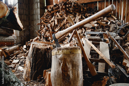 Canvastavla Axes in wooden chopping blocks and stacked firewood indoors