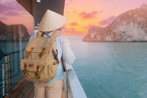 Canvastavla Traveler man exploring Halong bay at sunset with backpack and conical hat