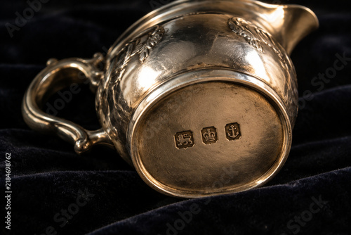 Antique silver cream jug with hallmark stamps on dark velvet, craftsmanship and heritage concept