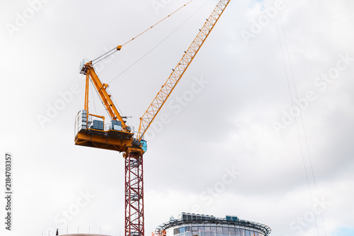 Bild auf Leinwand A large yellow construction crane stands tall against a cloudy sky