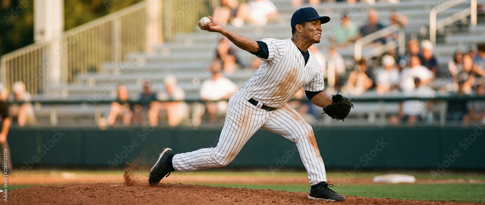 Fototapeta premium Pinstripe pitcher drives off mound during professional baseball game. Concept of power, speed, pitching mechanics and competition.