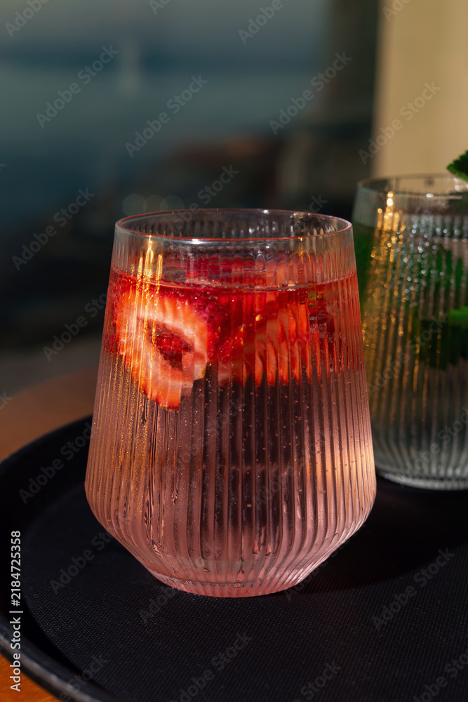 Obraz premium Strawberry lemonade with lime and fresh mint overlooking the sea at sunset 