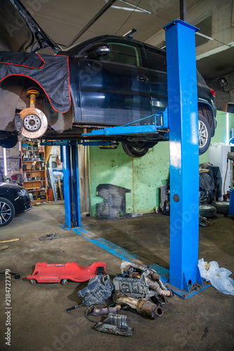Foto Car raised on hydraulic lift with wheel removed in auto repair shop