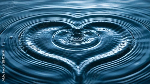 Water ripples form heart shape in calm water body at sunset