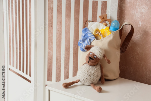 Baby bag with toys on chest of drawers in room