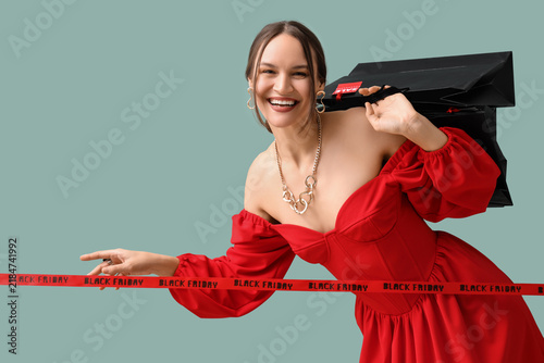 Happy young woman holding shopping bags and ribbon with text BLACK FRIDAY on ...