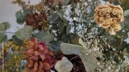 Elegantly arranged dried flowers in vintage glass bottles rotating smoothly on a natural wooden surface in warm lighting.