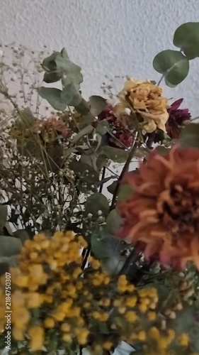 Elegantly arranged dried flowers in vintage glass bottles rotating smoothly on a natural wooden surface in warm lighting.