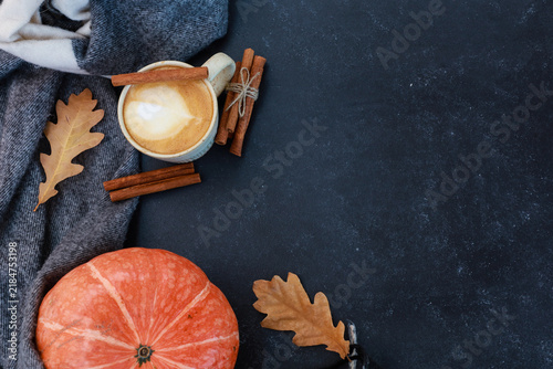 Spicy coffee and orange pumpkin on black background. Autumn coffee, hot warming tasty dink with cinnamon. Seasonal menu for coffee shop, cozy fall mood concept