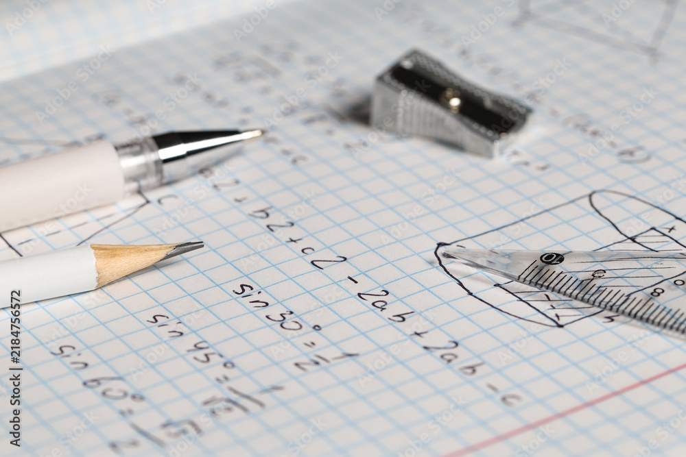 Obraz premium Copybook with handwritten maths formulas and stationery as background, closeup