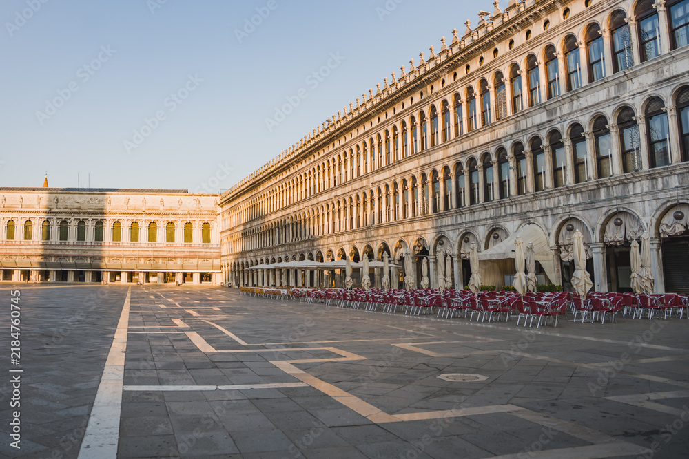 Obraz premium Wide view of historic Venetian architecture and the open square of Piazza San Marco in Venice, Italy, captured in soft evening light.