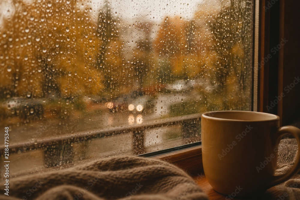 Obraz premium Cozy cup of hot drink on windowsill on rainy autumn day