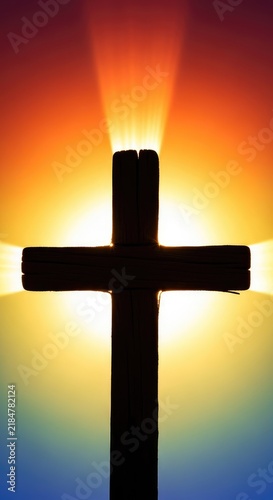 A dramatic close-up silhouette of a wooden cross positioned against a brilliant glowing light source, creating a powerful spiritual atmosphere, morning, atmospheric, wallpaper