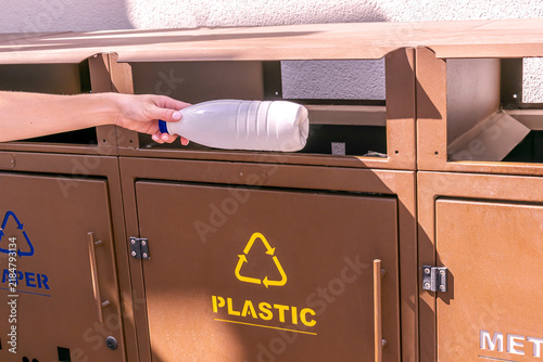 Obraz na płótnie Woman hand throwing trash bottle into bins for waste recycling