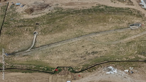 Aerial view of a construction site featuring concrete drainage infrastructure and dirt paths set within an undeveloped landscape in Longmont, Colorado, United States.