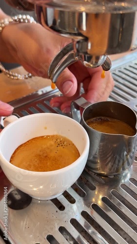 Close-up video of a barista extracting fresh espresso into cups from a professional coffee machine in a cafe